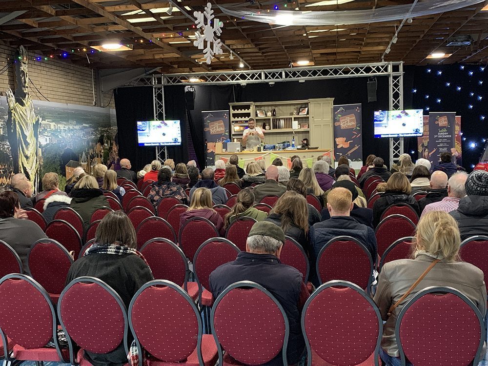 Cookery Demo being given by a chef on stage with a crowd of people sat watching