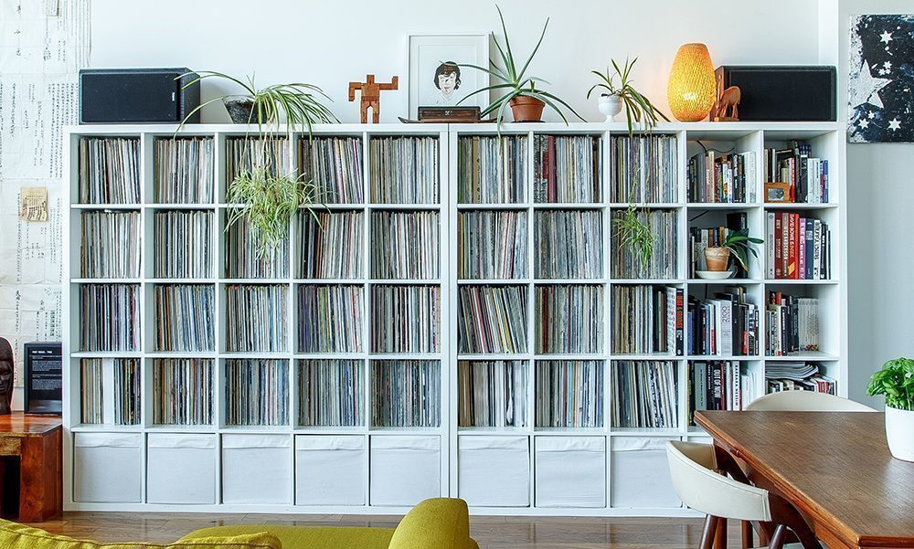 10 white bookcases in a row filled with books and records