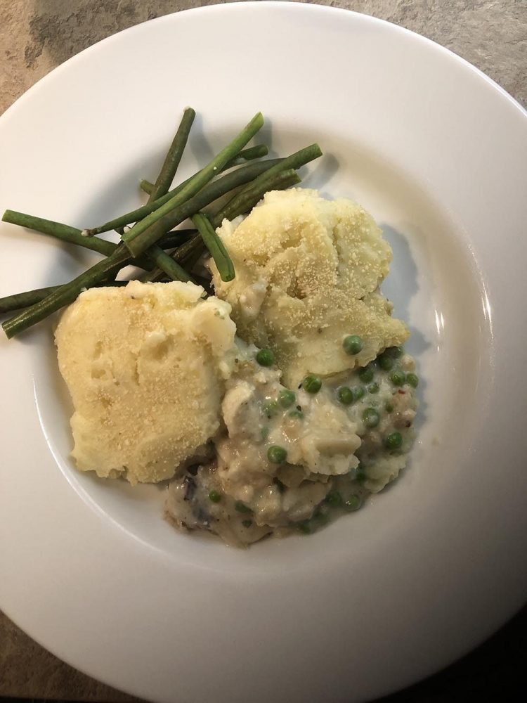 Fish Pie on white plate with a side of green beans
