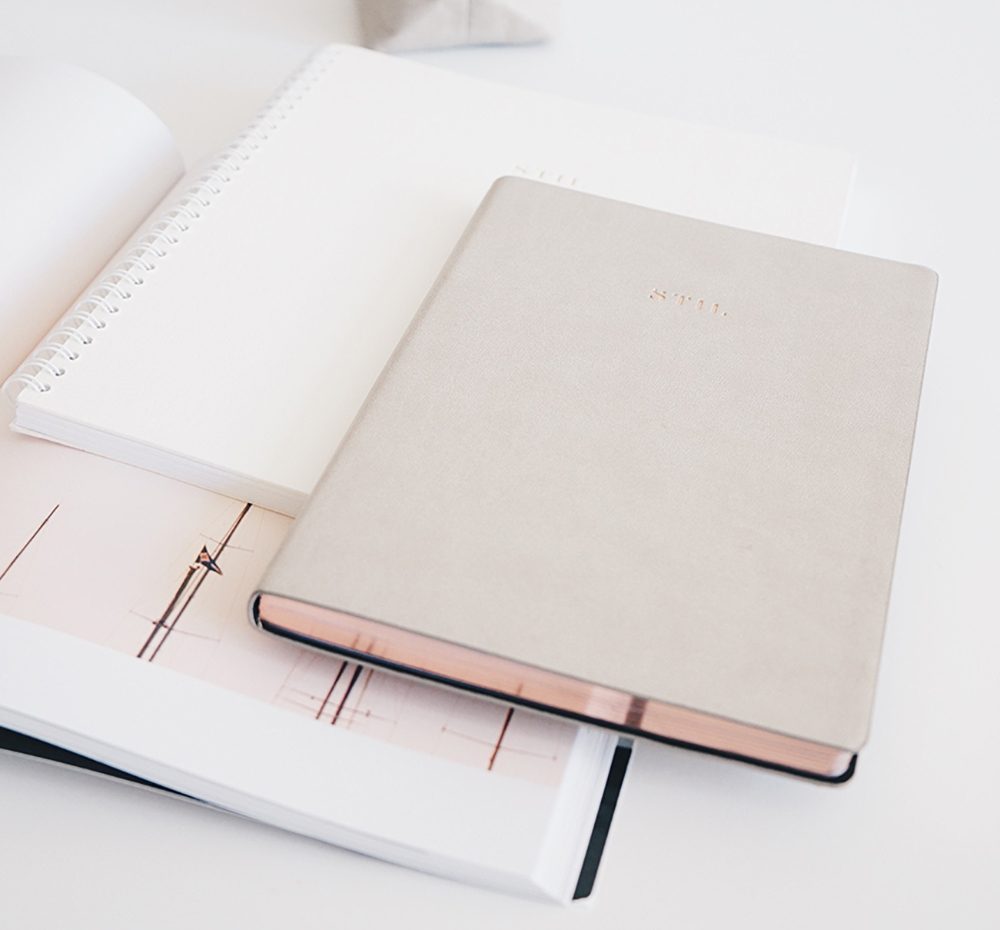 Gold notebook on top of white notebook on top of a planner
