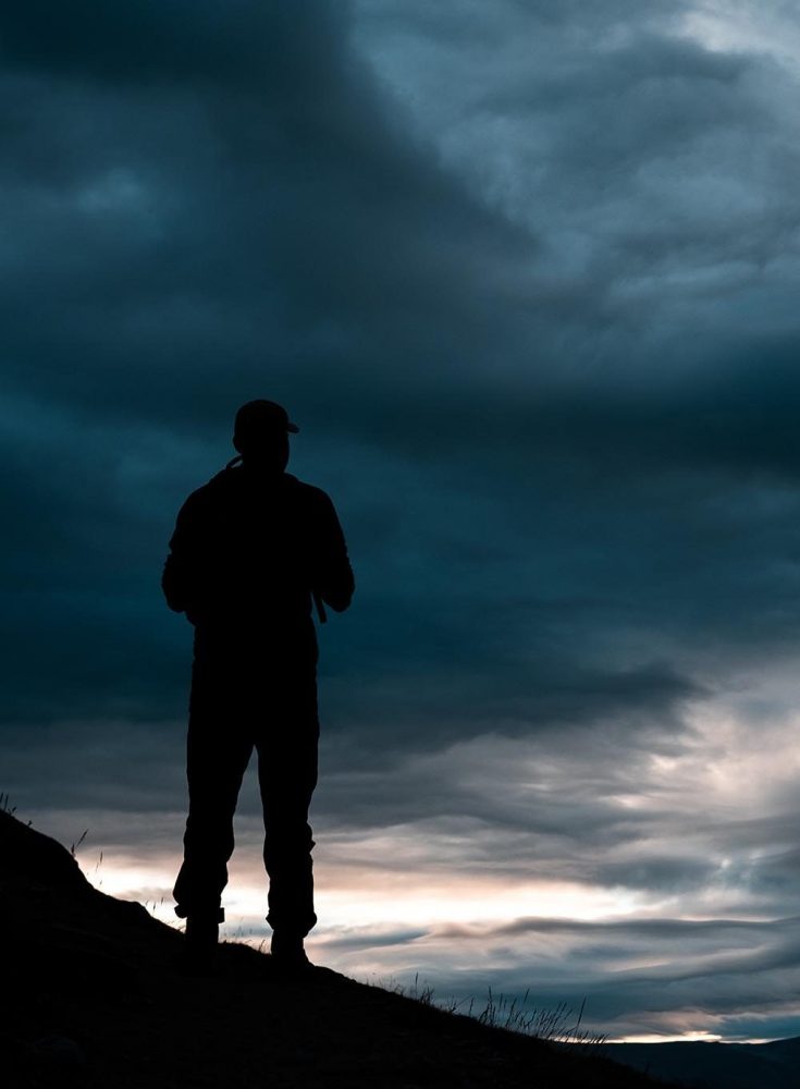 Man standing on his own looking out over a sunset. Support Group positives