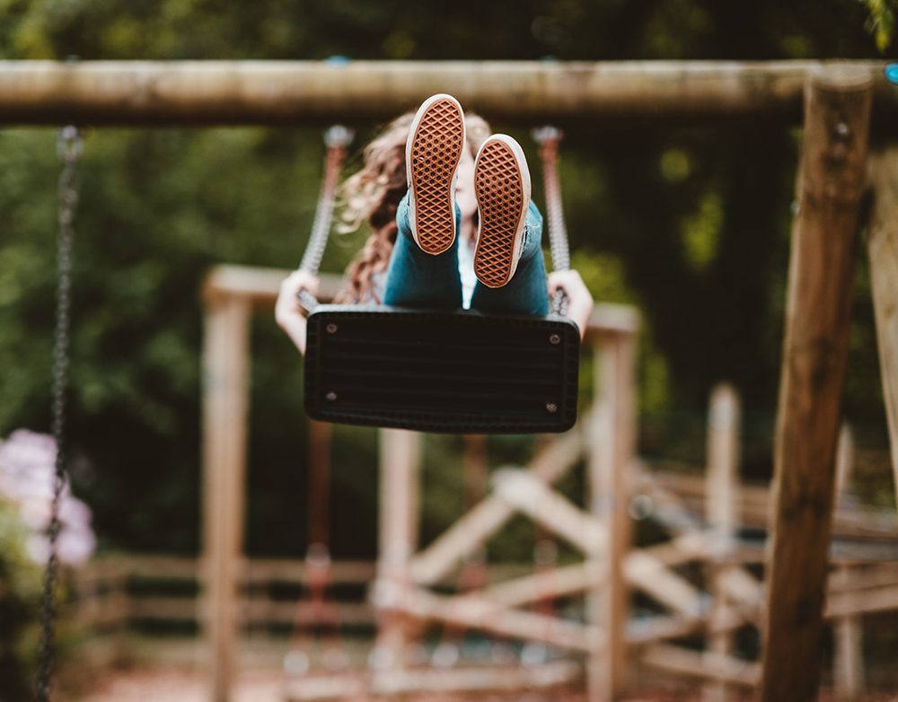 Child swinging on a swing, feet in the air