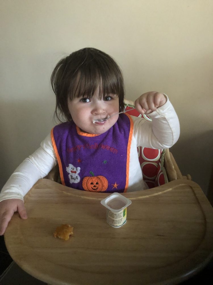 Lottie eating a yoghurt with a stainless steel spoon