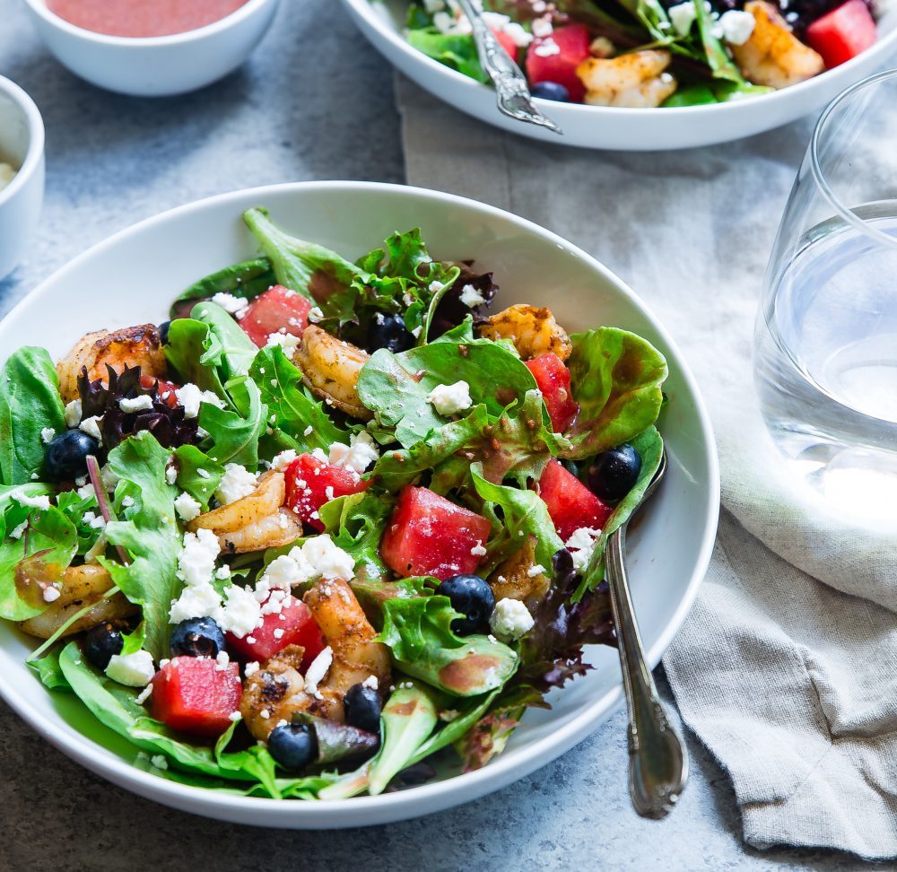 Salad bowl with spoon on white table cloth